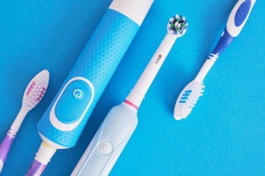 mavi arka planda farklı diş fırçaları, elektrikli diş fırçası veya plastik diş fırçası, çevre dostu yaşam tarzı konsepti, diş fırçalama etkinliği
