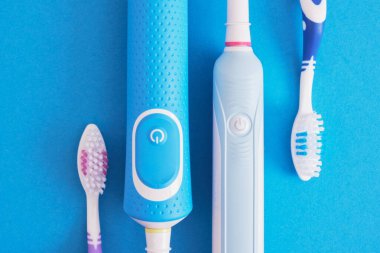 mavi arka planda farklı diş fırçaları, elektrikli diş fırçası veya plastik diş fırçası, çevre dostu yaşam tarzı konsepti, diş fırçalama etkinliği