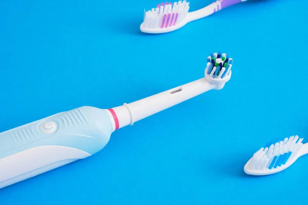 different toothbrushes on blue background, electric toothbrush or plastic toothbrushes, eco-friendliness lifestyle concept, efficiency of brushing teeth