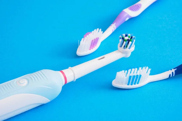 different toothbrushes on blue background, electric toothbrush or plastic toothbrushes, eco-friendliness lifestyle concept, efficiency of brushing teeth