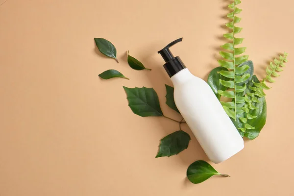 mock up organic cosmetic plastic bottle with dispenser and green leaves.