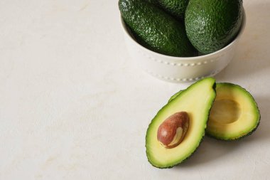 Avokado hafif desenli arka planda bir kasede, tohumlu kesilmiş avokado.