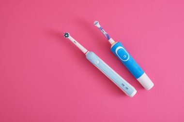 parlak pembe arka planda iki elektrikli mavi diş fırçası ağız hijyeni konsepti fotokopi alanı üst görünümü