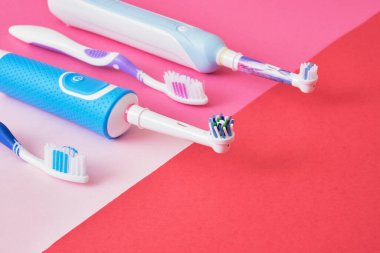 Pembe arka planda çeşitli diş fırçaları, elektrikli diş fırçaları veya plastik diş fırçaları, hangi fırçalar daha verimli ve çevre dostu