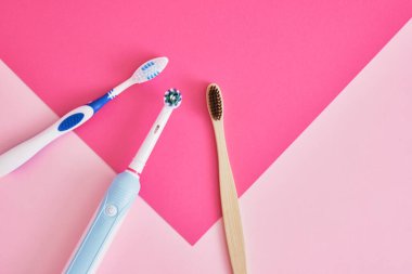 Pembe arka planda çeşitli diş fırçaları, elektrik, bambu ve plastik diş fırçaları, çevre dostu yaşam tarzı konsepti, plastik geri dönüşümü