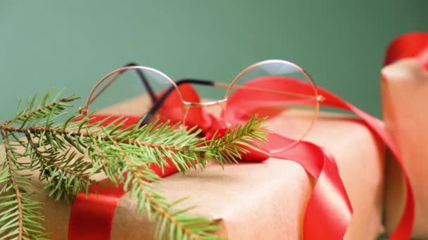 Eye glasses and gift boxes with red ribbon on green background copy space — Stock Video
