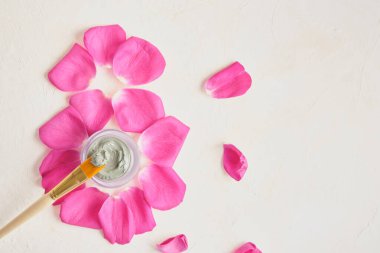 8 numara pembe gül yaprakları, kozmik fırça ve kavanozda mavi kil maske, bej rengi arka plan, kadınlar günü, 8 Mart, vücut bakımı, spa salonu hediye çeki.