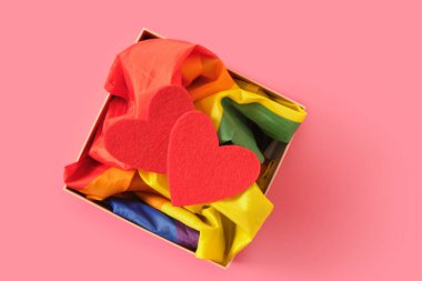 İki kırmızı keçeli kalp, bir kutuda Igbt topluluğunun gökkuşağı sembolü, pembe arka plan, sevgililer günü konsepti, eşcinsel çiftler için romantizm