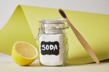 Bambu diş fırçası, etiketli bir kavanozda soda ve limon bezi ve yeşil arka plan. Doğal diş beyazlatma, çevre dostu yaşam tarzı.