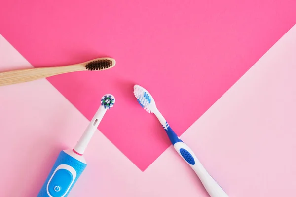 several different types of toothbrushes on a pink background, electric, bamboo and plastic toothbrushes, environmental friendliness lifestyle concept, plastic recycling