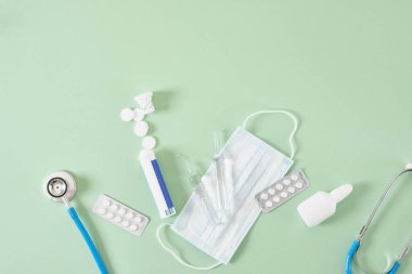 Soğuk algınlığı ve grip tedavisi. Çeşitli ilaçlar, tıkalı bir burundan fışkıran spreyler ve yeşil bir arka planda boğaz ağrısı. Uzayı kopyala Medicine flat lay.
