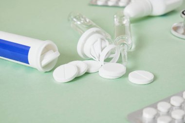 Soğuk algınlığı ve grip tedavisi. Çeşitli ilaçlar, tıkalı bir burundan fışkıran spreyler ve yeşil bir arka planda boğaz ağrısı. Uzayı kopyala Medicine flat lay.