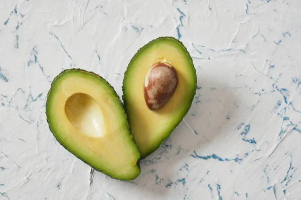 Twee Helften Van Een Avocado Liggen Een Hartvorm Vers Geheel — Stockfoto