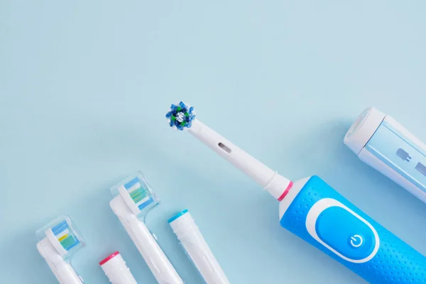Ηλεκτρική Οδοντόβουρτσα Και Πολλά Διαφορετικά Πολύχρωμα Αντικαταστάσιμα Ακροφύσια Μπλε Φόντο — Φωτογραφία Αρχείου