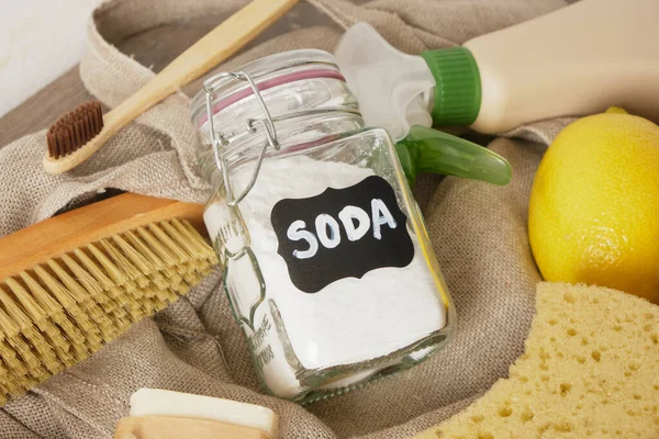 eco cleaning set on table, jar of soda, lemon and natural non-toxic cleaners, soap, luffa and wooden brush, zero waste lifestyle close up