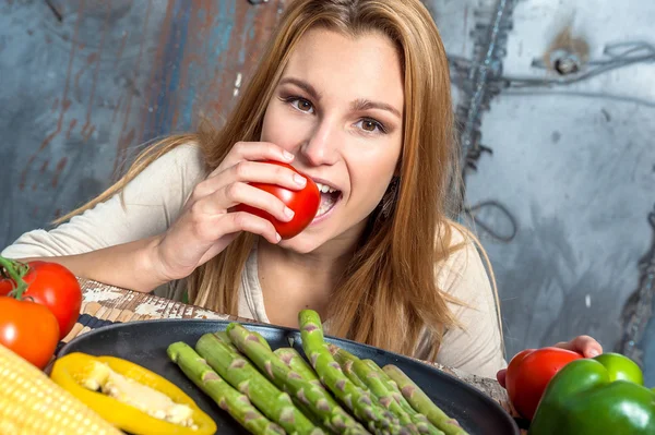 Ung kvinna biter en tomat — Stockfoto