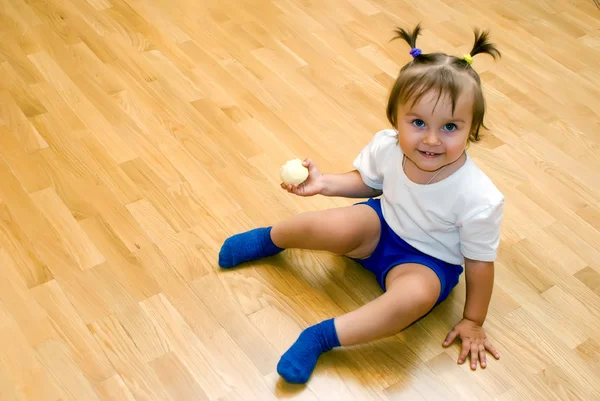 Little girl sat on the floor with peeled apple — Stock Photo, Image