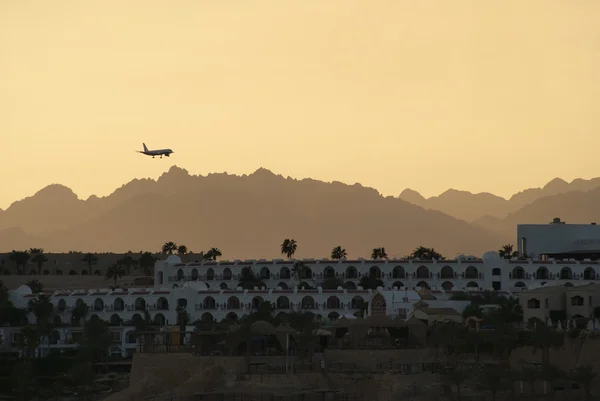 Vliegtuig landt op de achtergrond van de bergen en het hotel — Stockfoto