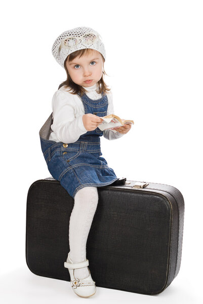Pretty little girl with book sitting on suitcase and pout