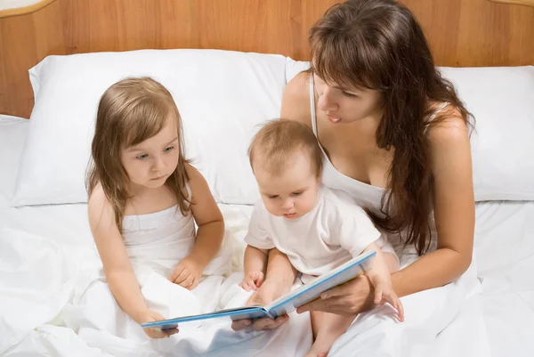 Мать читает детям книжку с рассказом о времени сна — стоковое фото
