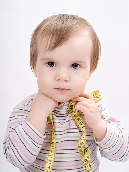 Adorable baby girl with a measuring tape in hands — Stock Photo, Image