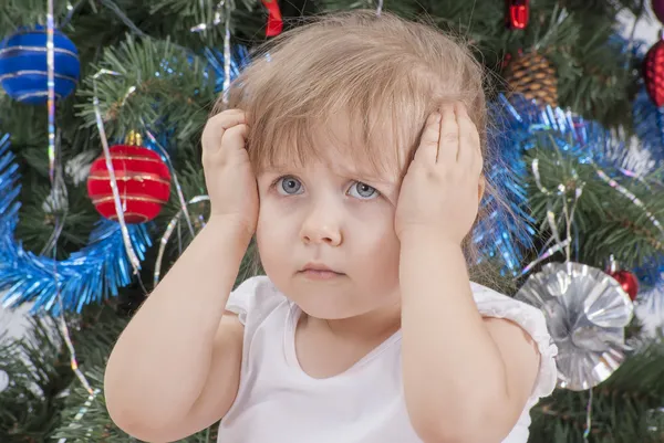 Portrait of upset little girl near the Christmas tree — Stock Photo, Image