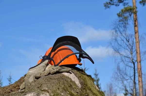 Helmet and gloves on a rock — Stock Photo, Image
