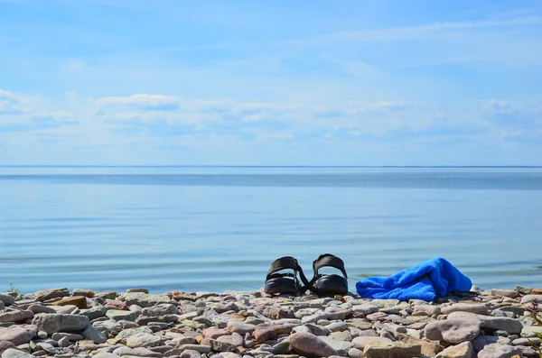 Schuhe und Handtuch an der Küste — Stockfoto