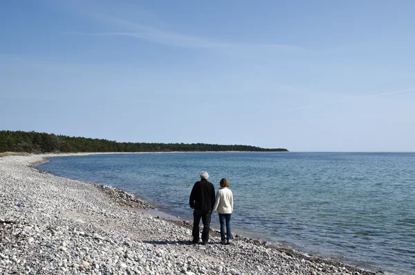 Senior couple walks along coast — Stock Photo, Image