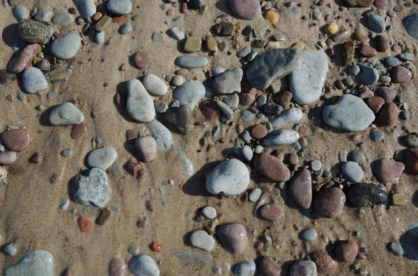 Detalhe de uma praia de areia molhada com seixos lisos — Fotografia de Stock