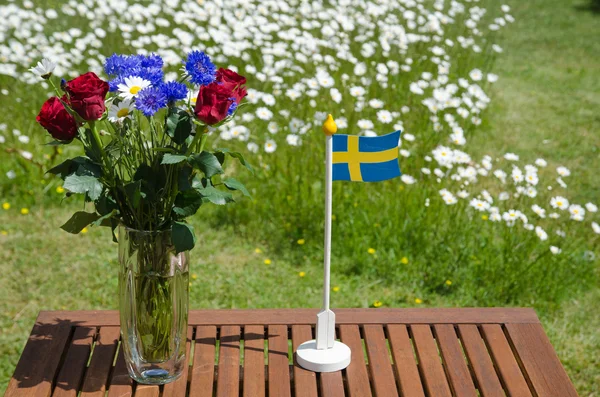 Table with summer flowers and a swedish flag — Stock Photo, Image