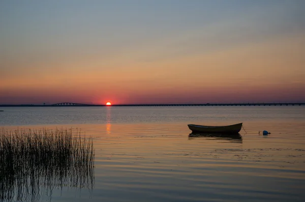 在平静的水面，在夕阳中的孤独划艇 — 图库照片