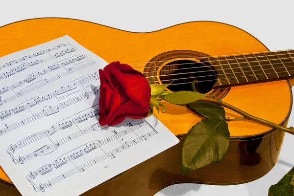 Una guitarra y una rosa sobre un fondo claro . — Foto de Stock