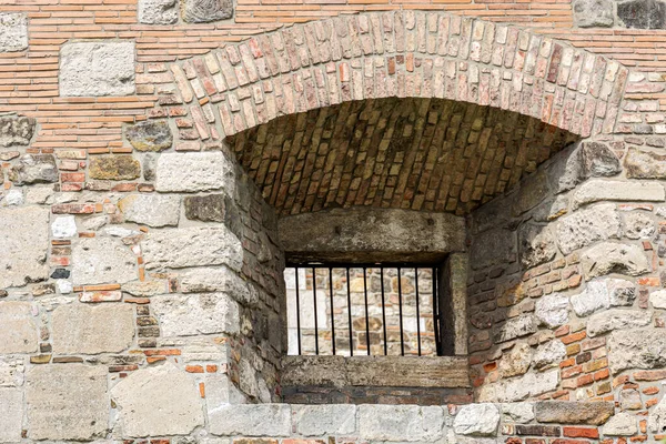 レンガ造りのアーチを持つ厚い石の要塞の壁のうつ病で鉄ロッドの格子窓 — ストック写真