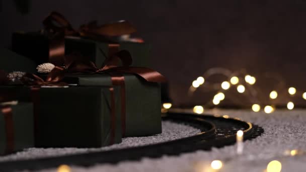 Treno giocattolo elegante cavalca sulla ferrovia sotto l'albero di Natale con molte scatole regalo. — Video Stock