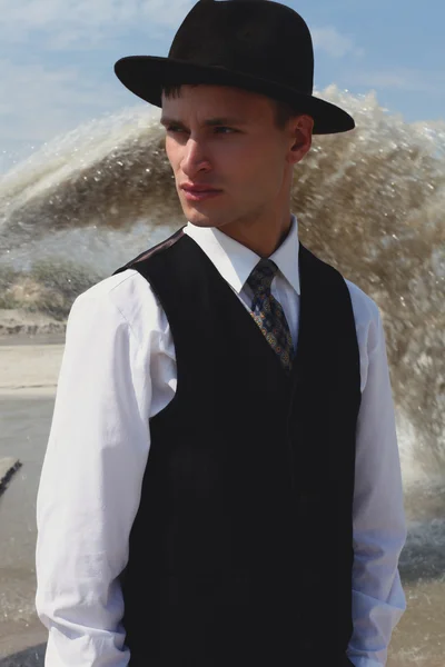 Beautiful brutal man in a classic suit. Cowboy in the desert near the river water. Fashion and Beauty. Black and white in nature — Stock Photo, Image