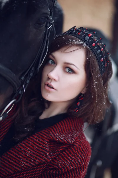 Menina encantadora e bonita da morena de aparência europeia com cavalo marrom na natureza de inverno com acessórios. Moda e beleza. Animais e naturais . — Fotografia de Stock