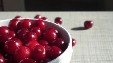 Beyaz tuğladan bir duvarın arkasında kırmızı taze kirazlı dönen bir kase. Yüksek kaliteli FullHD görüntüler