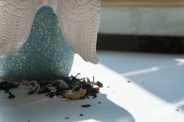 Beyaz arka planda çeşitli otlarla gölgeli bir fincan bitki çayı.