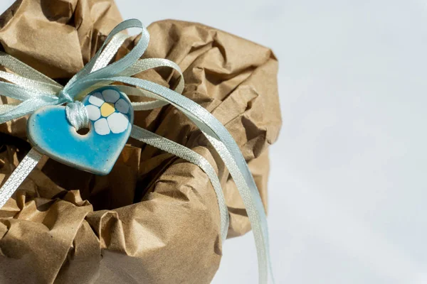 Wrapping brown craft paper package with ribbon as present. Hand made parcel bag gift. White background with shadows.