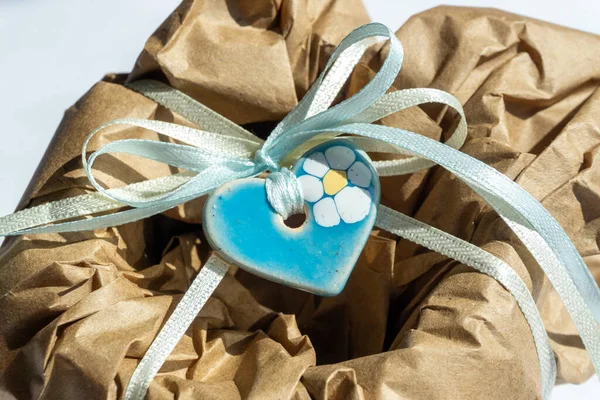 Wrapping brown craft paper package with ribbon as present. Hand made parcel bag gift. White background with shadows.
