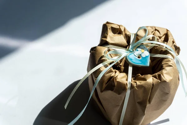 Wrapping brown craft paper package with ribbon as present. Hand made parcel bag gift. White background with shadows.