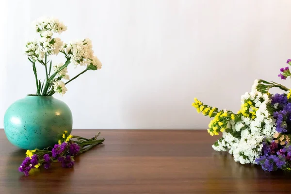 Colorful bouquet of dried flowers on the wooden table and round turquoise ceramic vase with white flowers.  Front view. Copy space. White background