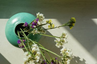 Beyaz masadaki turkuaz vazoda kurumuş çiçekler. Görünümün üstünde.