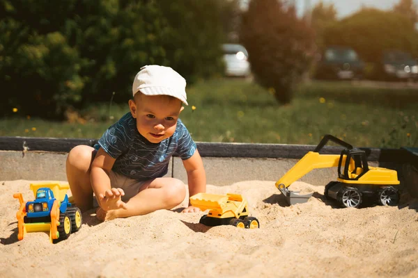 Child playing in sandbox. Little boy having fun on playground in sandpit. Outdoor creative activities for kids. Summer and childhood concept.