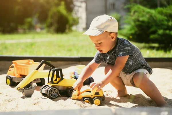 Child playing in sandbox. Little boy having fun on playground in sandpit. Outdoor creative activities for kids. Summer and childhood concept.
