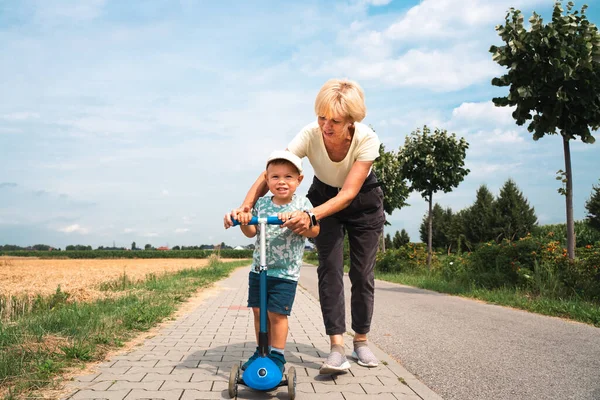 Grandmother Supporting Holding Her Years Old Grandson Ride Scooter Sunny —  Fotos de Stock