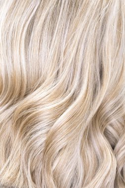 Hair coloring women close up texture background. Bunch of shiny straight blond hair in a wavy curved style. Copy space