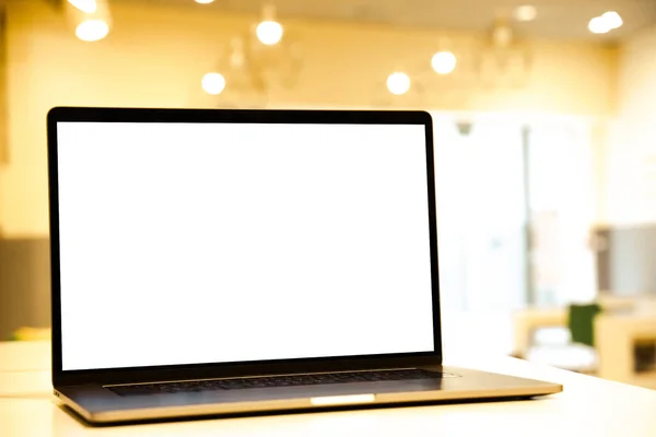 Laptop with white screen in business office or shopping mall. Empty copy space, blank screen mockup. Soft focus laptop with interor background. Travel, study and office work concept.