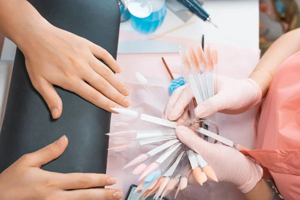 Manicure salon client choosing color of nail polish for manicure from palette colors. Woman getting nail manicure. Professional manicure in beauty salon. Nail art, hands care, beauty industry concept.